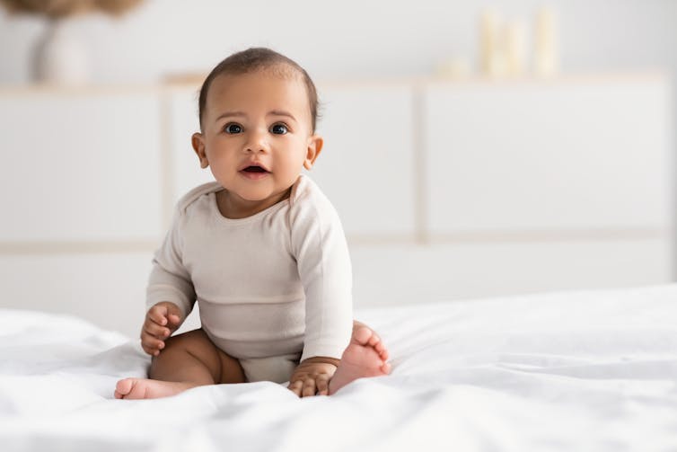 A baby sitting on a bed.