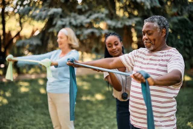 People stretch bands in outside exercise class