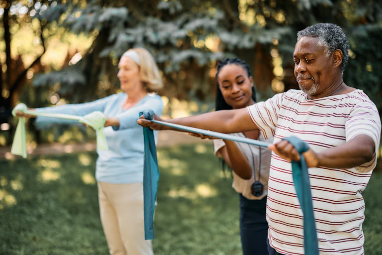 People stretch bands in outside exercise class