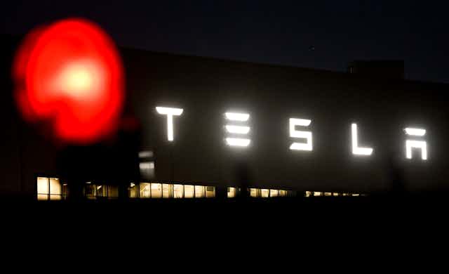 The Tesla logo is displayed on an exterior wall of a Tesla factory. 
