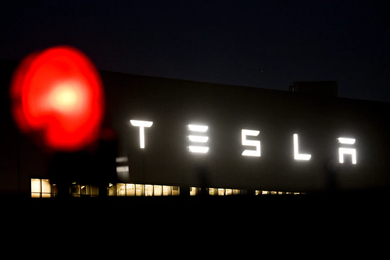 The Tesla logo is displayed on an exterior wall of a Tesla factory.