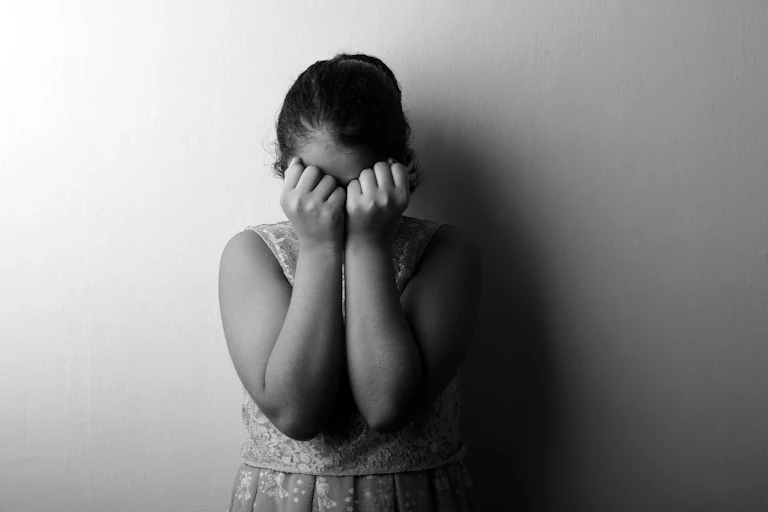 A female child covers her face.