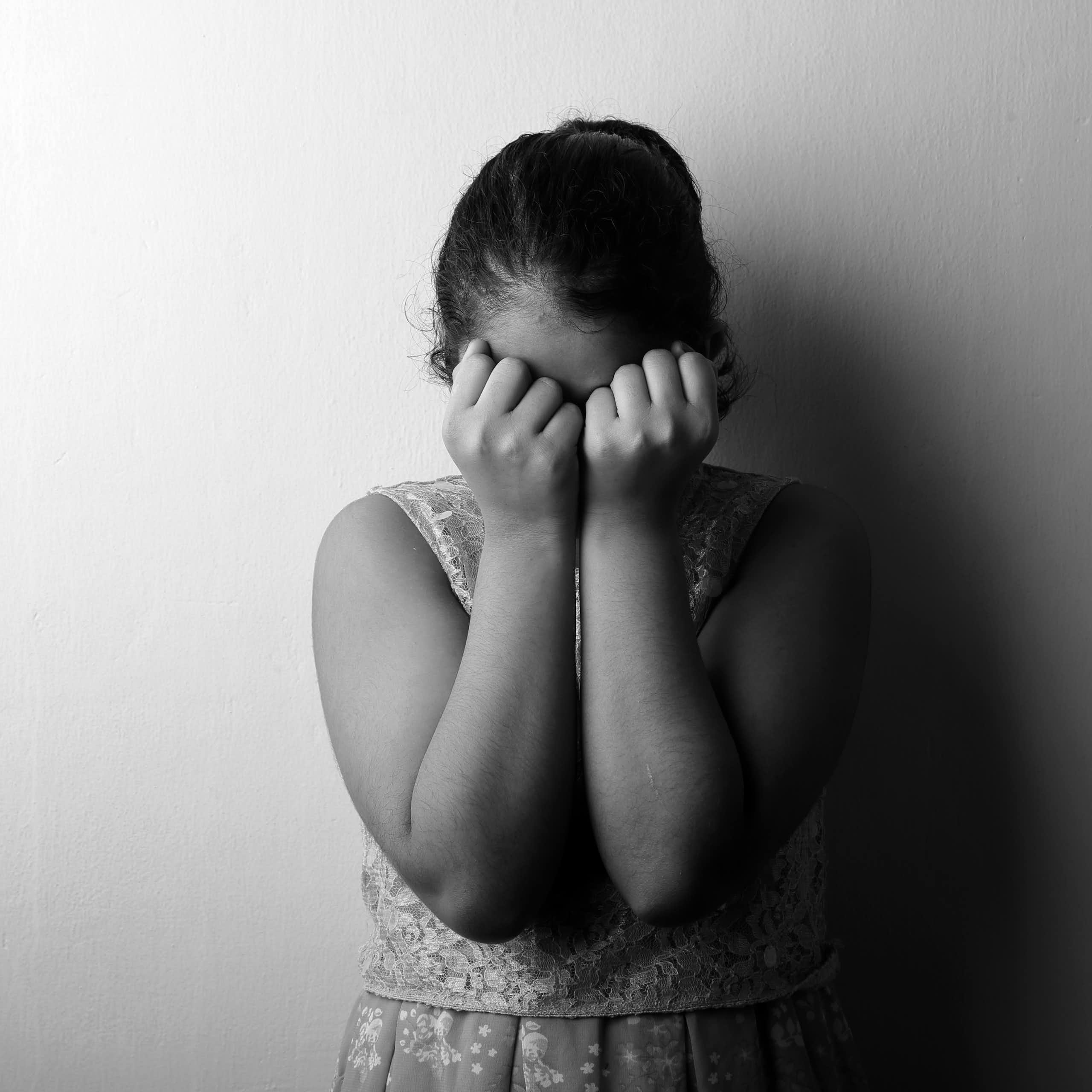 A female child covers her face. 