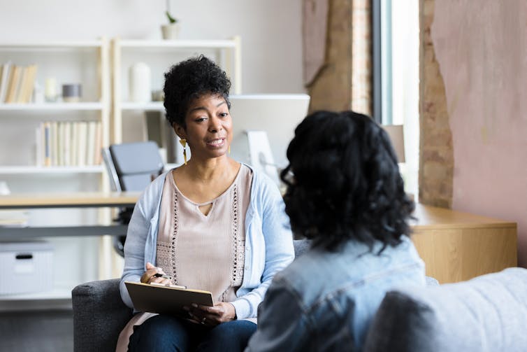 A therapist listens to a young female speak.