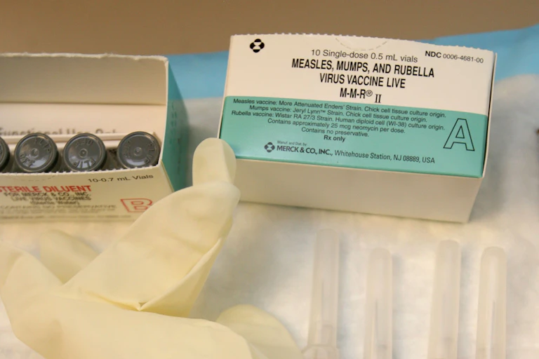 An open box of MMR vaccine, an open box, containing four vials of the vaccine, a pair of disposable medical gloves and four syringes containing the vaccine