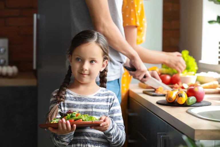 Une petite fille préparant une salade avec ses parents