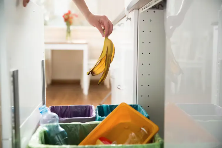 main qui jette une banane dans la poubelle