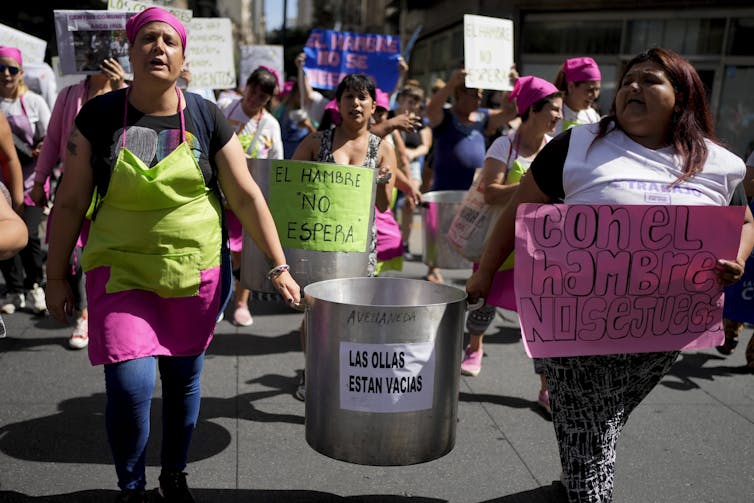 Mujeres manifestándose, dos de ellas portando un contenedor metálico