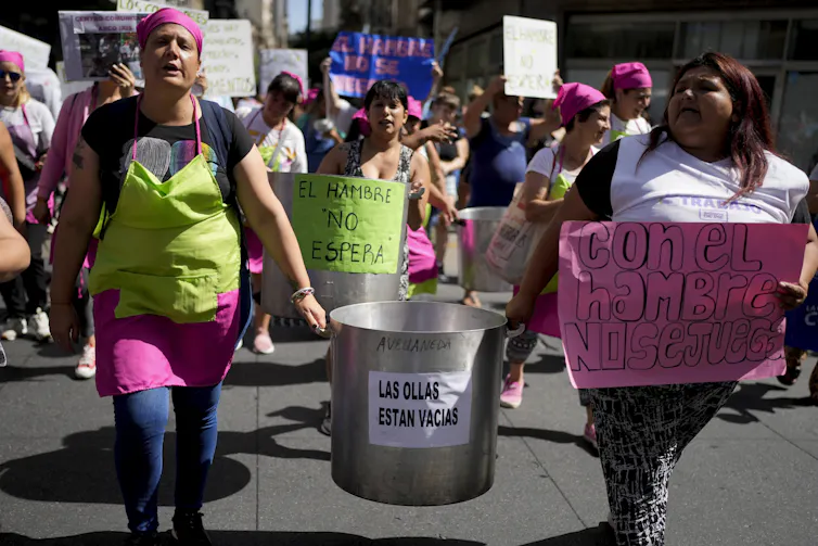 Women demonstrating, two of them carrying a metal container