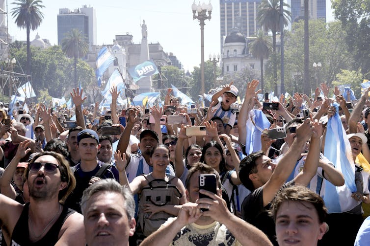 Personas marchan por una calle, portando banderas argentinas