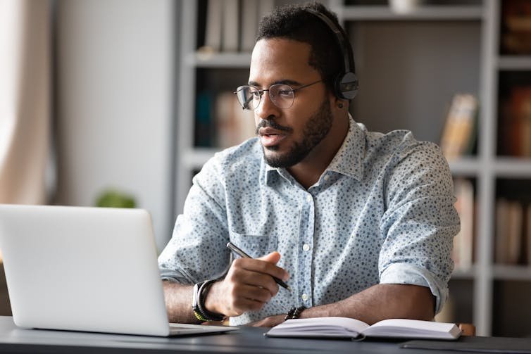 A young Black man working on a laptop.