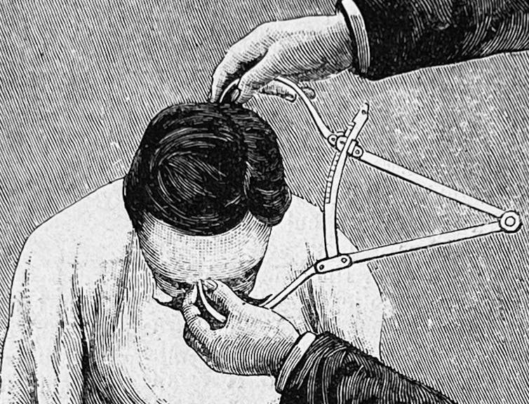 Pen and ink illustration of suited hands using calipers to measure a man's forehead to back of his head