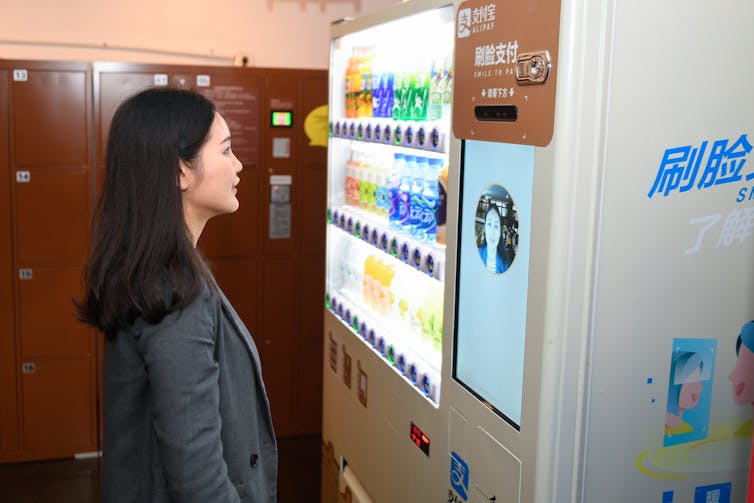 Woman looks at screen with her image on a vending machine
