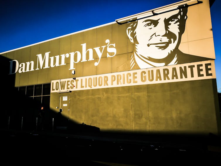 A Dan Murphy's liquor store sign reflects golden sunlight.