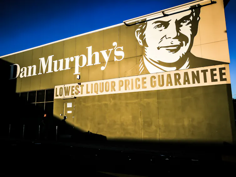 A Dan Murphy's liquor store sign reflects golden sunlight.