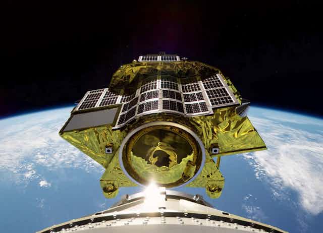 A small spacecraft with golden foils shining above Earth horizon
