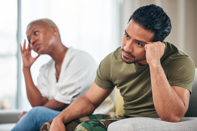 A man and a woman sit side by side, looking worried