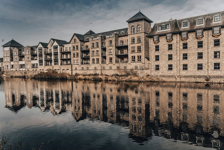 A row of buildings reflected in a body of water.