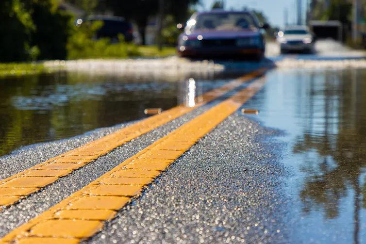 Cars driving down a flooded road in the US.