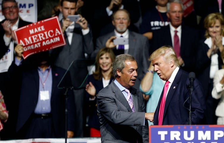 Nigel Farage and Donald Trump shaking hands on stage.