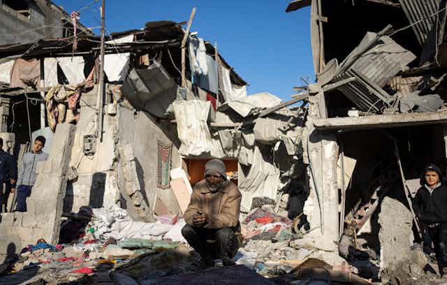 A man sits amid piles of rubble, a young boy to his right.