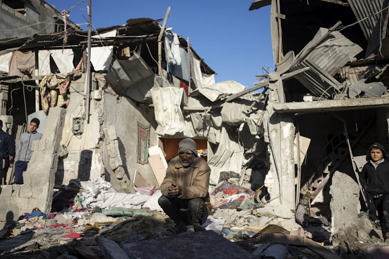 A man sits amid piles of rubble, a young boy to his right.
