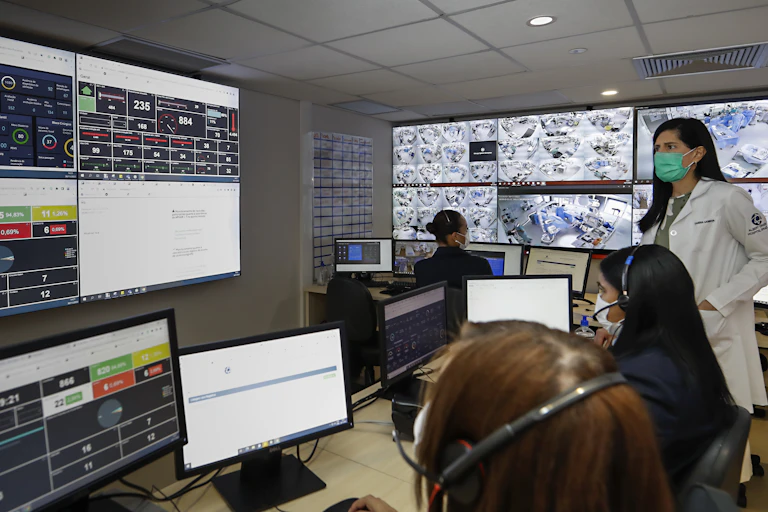 Doctor and assistants work in a room full of computers and digital panels