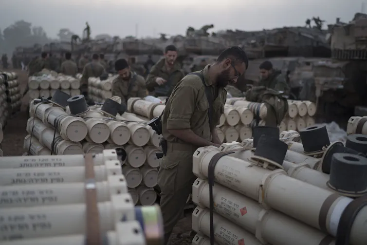 Soldiers stand near piles of cylinders.
