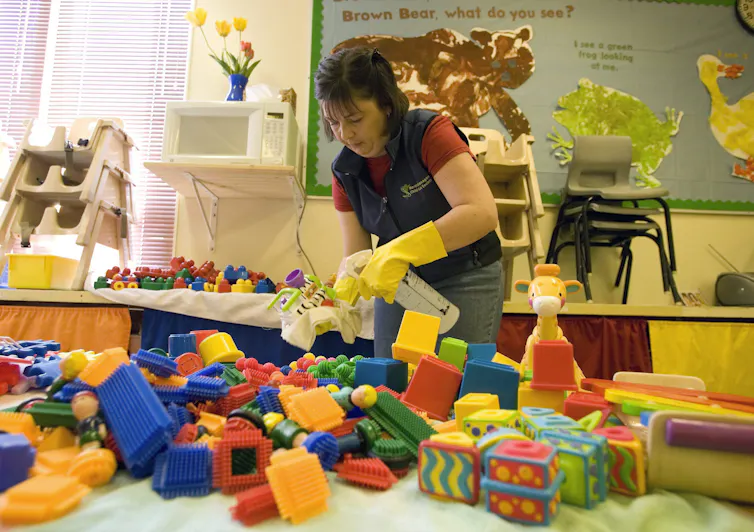 A person seen cleaning children's toys in a classroom.