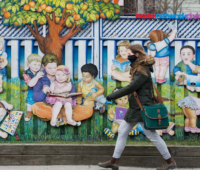 A person seen walking past a child care with a mural of children.