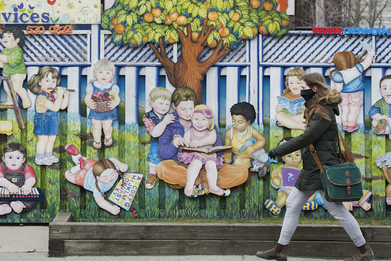 A person seen walking past a child care with a mural of children.