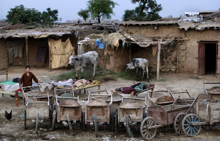 Wooden carts and people sleeping on beds outside their homes in an informal settlement