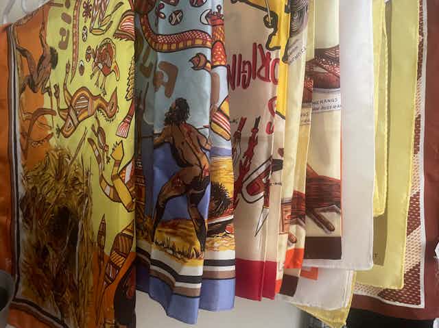 Several hanging scarves depict First Nations people and themes