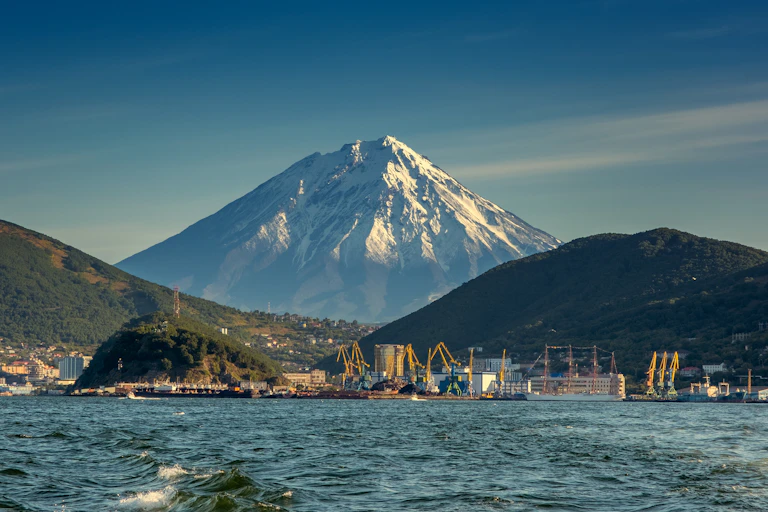A view from out to sea of a city with a volcano in the background.