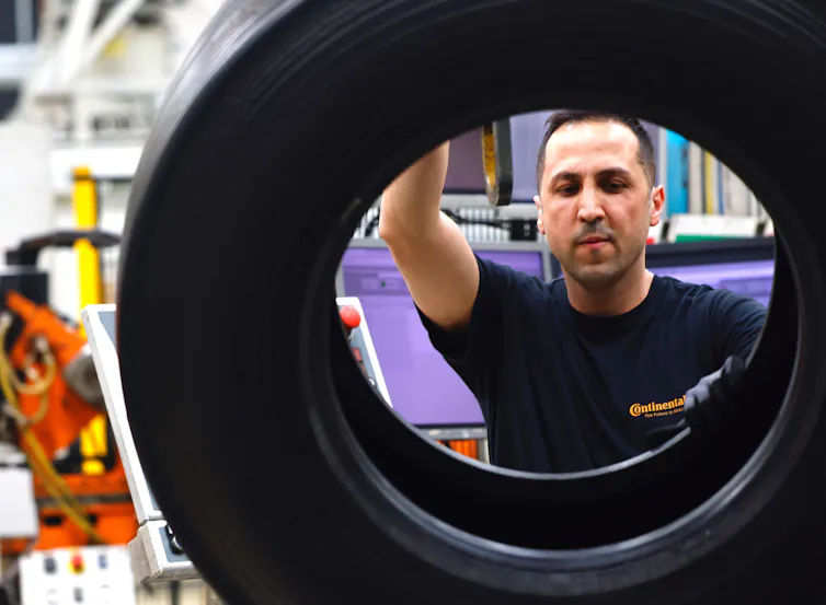 Factory worker behind a car tyre