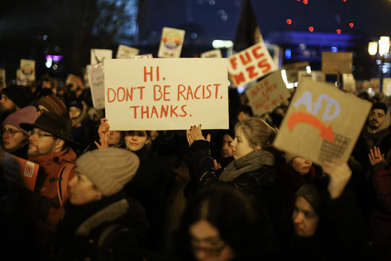 Des personnes brandissent des pancartes proclamant notamment « Hi. Don't be racist. Thanks. »