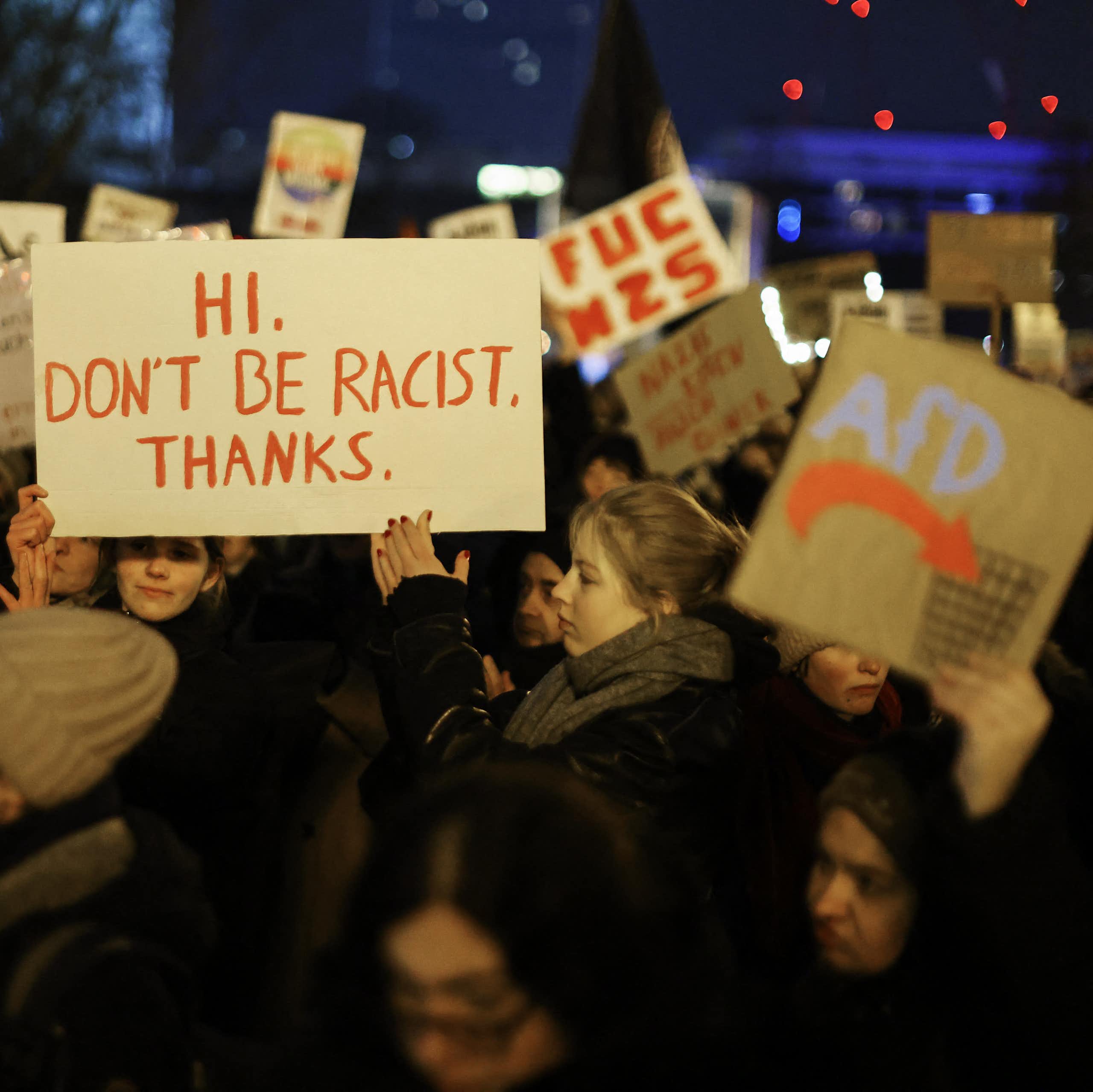 Des personnes brandissent des pancartes proclamant notamment « Hi. Don't be racist. Thanks. »