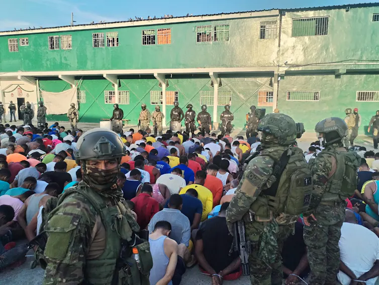 Soldiers with guns standing around kneeling prisoners.