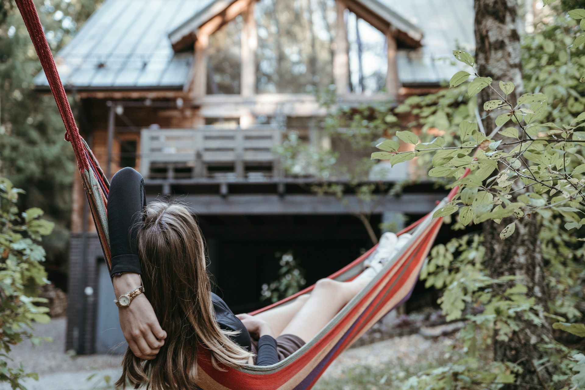 Woman relaxing in hammock in garden.
