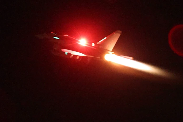 An military jet heads upward with a trail of exhaust behind it.