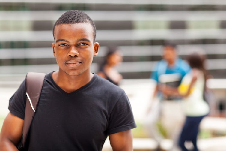 A Black teenage boy carrying a backpack poses for a photo.