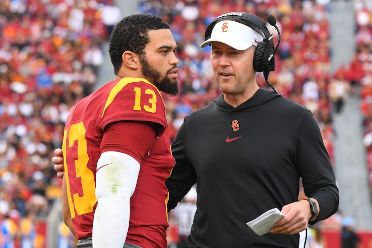 USC football player Caleb Williams talks with head coach Lincoln Riley in stadium