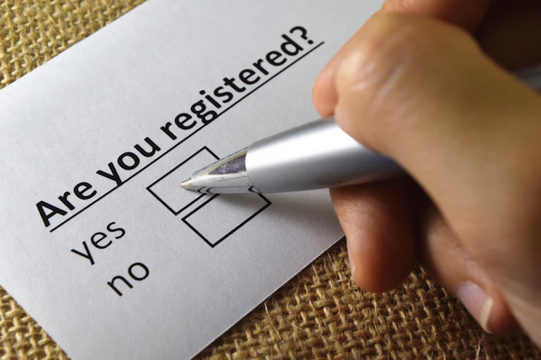 A person ticking a 'yes' box on a form that asks 'are you registered?'