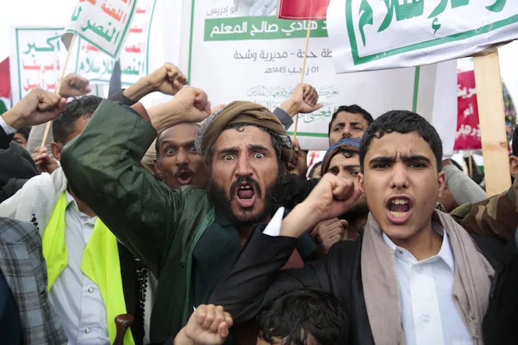 Men raise their fists with angry expressions on their faces.