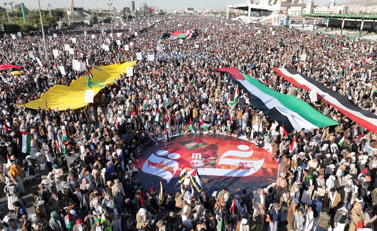 Large crowd protesting in Yemen holding Palestinian and Hezbollah flags