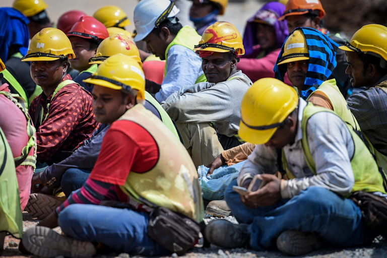 Workers wearing hardhats sitting on the ground