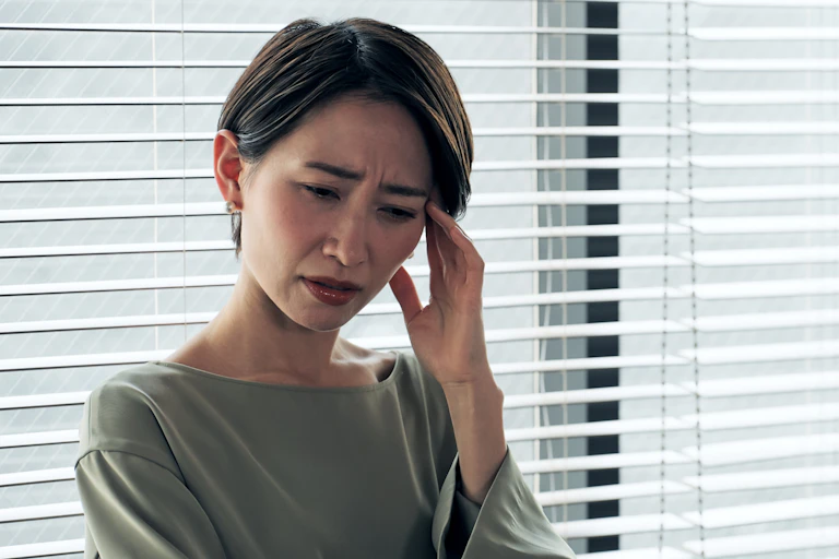 Woman holds head at work