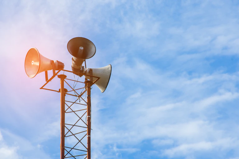 three loudspeakers mounted on a scaffold with a blue sky in the background