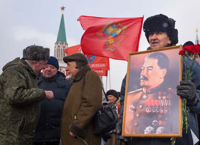 Russian man holds portrait of the late Soviet dictator Josef Stalin.