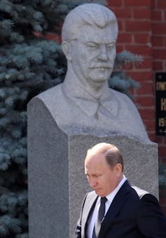 Russian President Vladimir Putin walks statue of Soviet leader Josef Stalin.